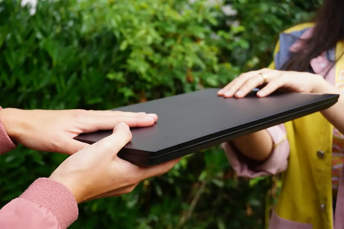 Zwei Personen halten gemeinsam einen Laptop in ihren Händen