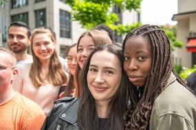 Gruppenselfie von GF-H Ratsuchenden draußen. Im Hintergrund sind Bäume und ein Gebäude abgebildet. 